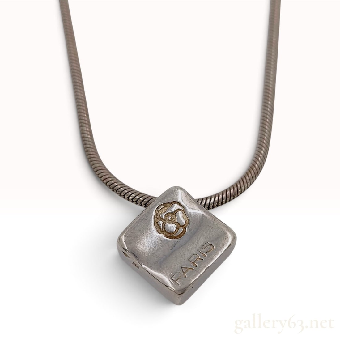 Vintage Chanel Camellia and Coco Sterling Silver Pendant Necklace: This Chanel pendant necklace is crafted from sterling silver and features a square slide pendant on a snake chain. The pendant is decorated with iconic house motifs including an embossed camellia flow