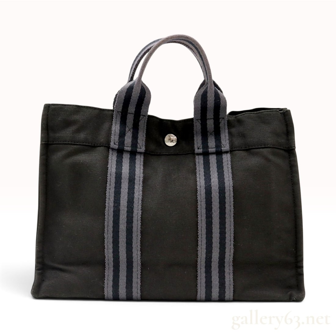 Hermes Fourre Tout Herline Black Canvas Tote Bag: This Hermes Fourre Tout Herline tote bag is crafted from black woven cotton canvas with dual vertical webbing straps. The webbing features a repeating grey and black striped pattern and extends upward