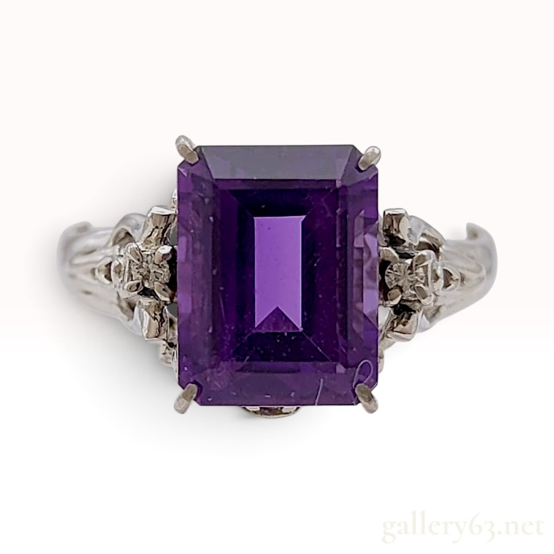 Vintage Platinum Amethyst and Natural Diamond Cocktail Ring: This vintage platinum cocktail ring centers a large emerald-cut amethyst of deep purple hue. The primary gemstone measures approximately 12mm by 9mm and is secured by a four-prong setting. The shoulde