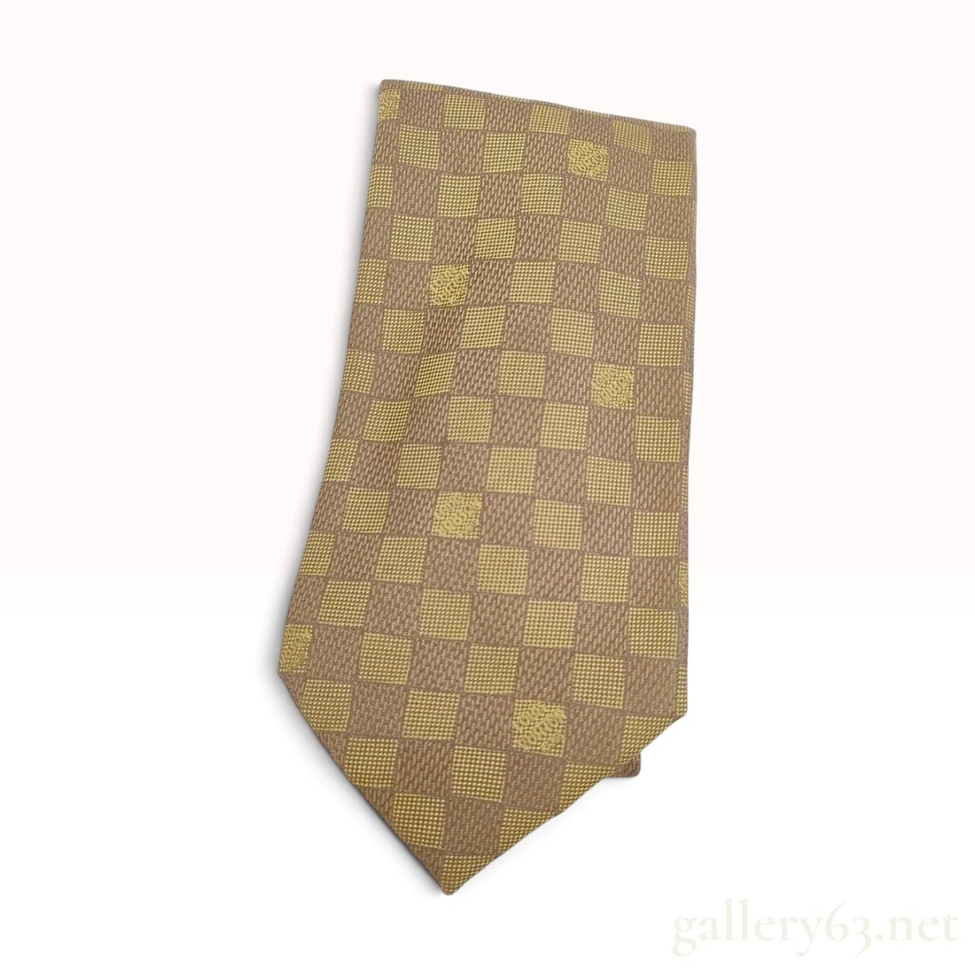 Louis Vuitton Damier Pattern Gold Tone Silk Necktie: This Louis Vuitton necktie is crafted from 100% silk and features the signature Damier checkered pattern in a palette of tan and golden yellow tones. The jacquard weave alternates between diagonal rib