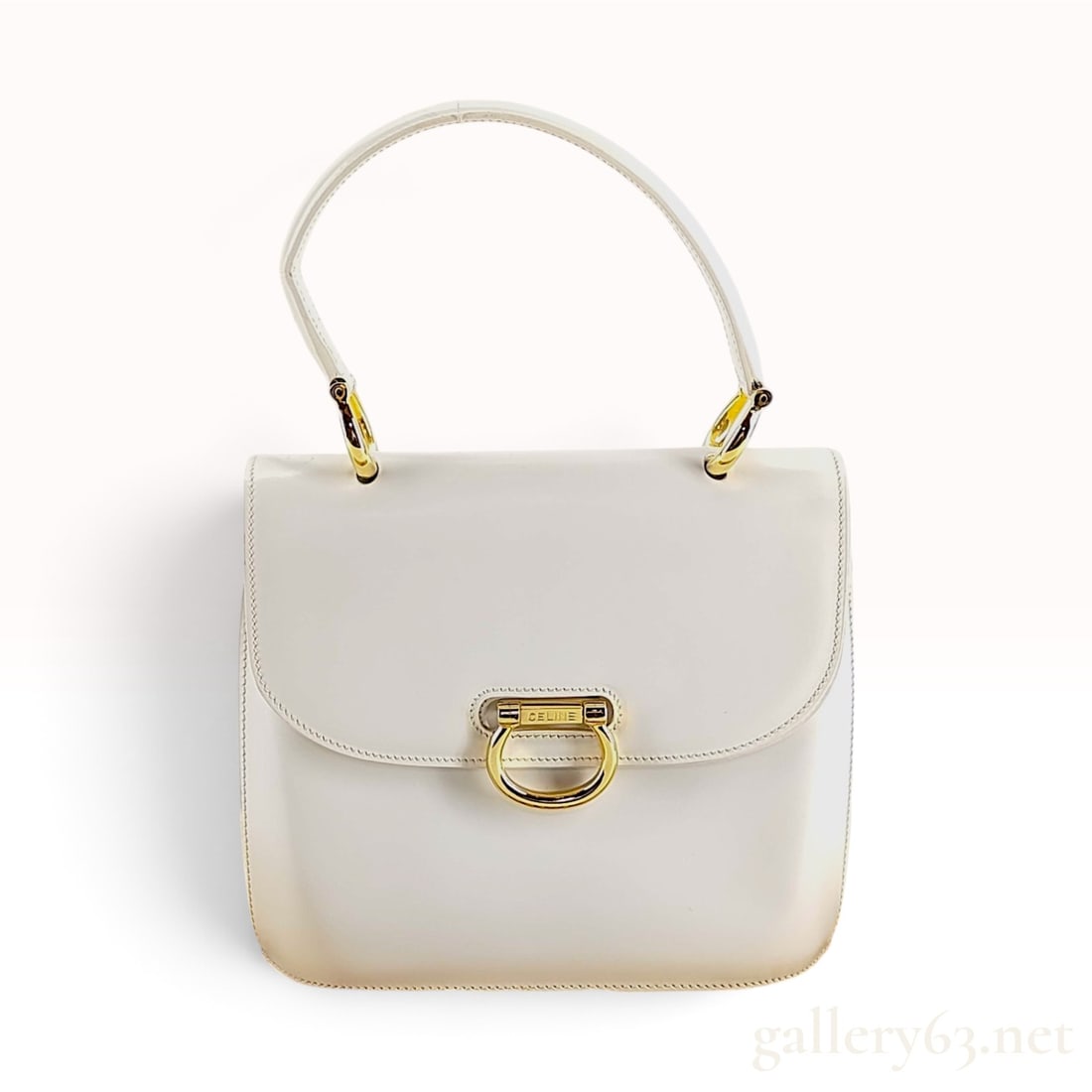 Vintage Celine White Leather Top Handle Bag: A vintage Celine top handle bag crafted from smooth white leather. The bag features a structured trapezoidal silhouette with a gusseted accordion side profile. It is designed with a single leather han