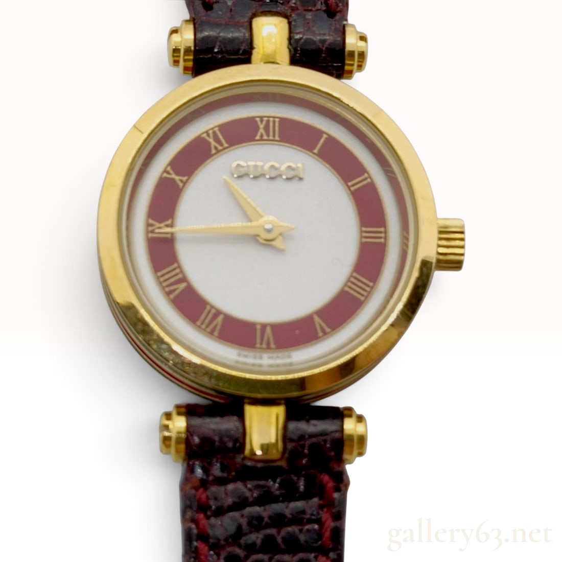 Vintage Gucci 2000L Maroon Enamel and Gold Tone Ladies Wristwatch: This vintage Gucci 2000L ladies wristwatch features a circular gold-tone case accented by signature red and green enamel stripes along the side profile. The two-tone dial presents a white center with 