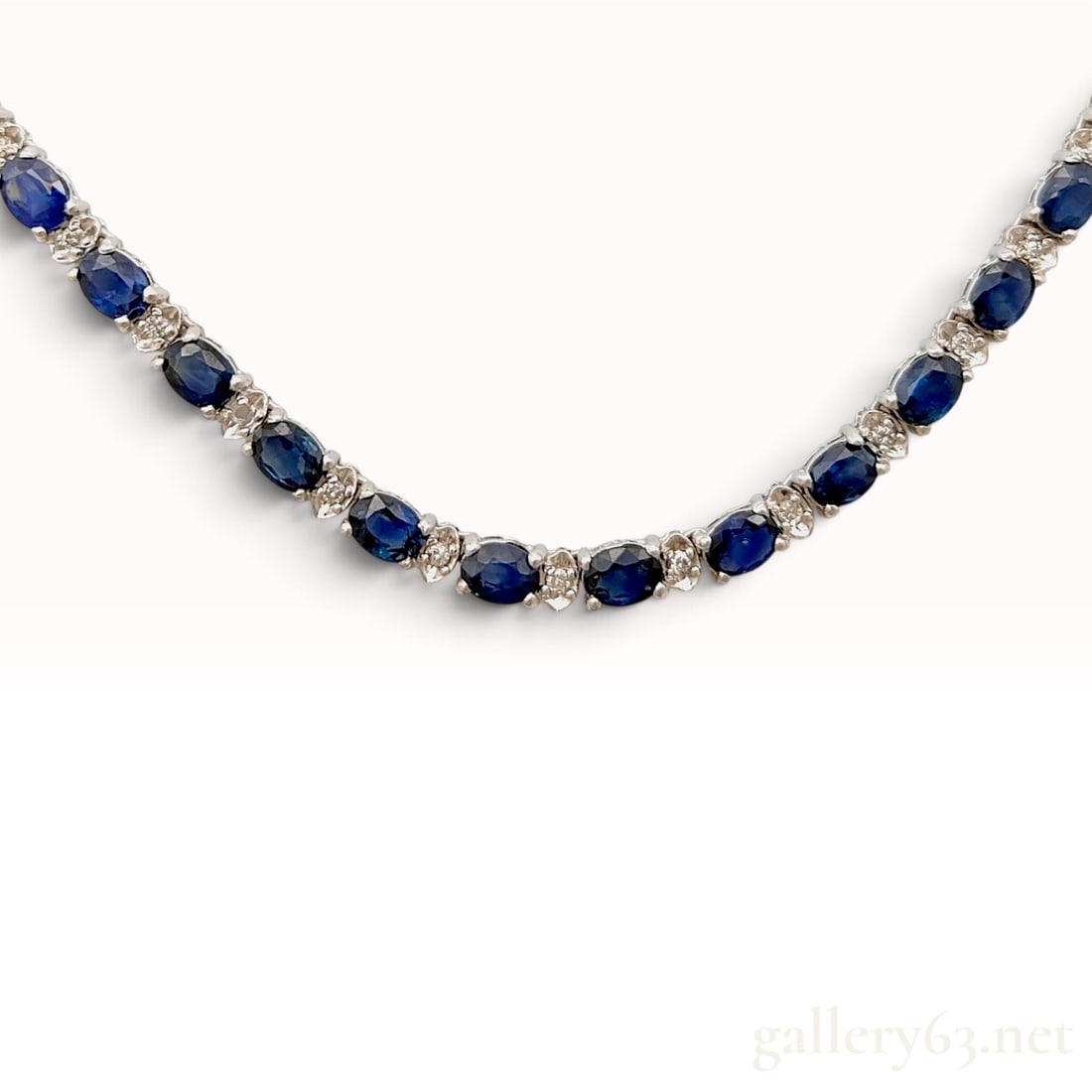 7.80ctw Sapphire and 0.80ctw Natural Diamond 18KWG Tennis Necklace: This 18 karat white gold necklace is designed in a classic tennis-style line, featuring a continuous strand of alternating diamonds and sapphires. The piece is set with oval-cut sapphires of a medium 