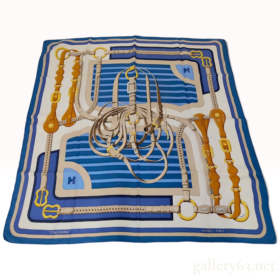 Hermes Coaching Navy and Light Blue Silk Carre 90: This Hermes silk carre 90 crafted from silk twill features the Coaching pattern designed by Julia Abadie. The design is centered on a coiled pile of leather harness straps and buckles, with the corner