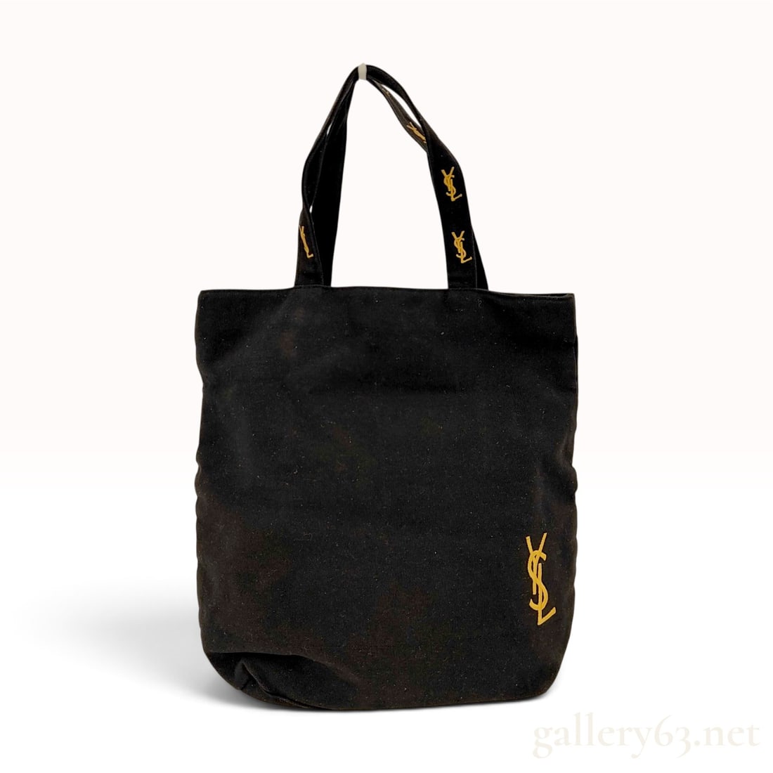Yves Saint Laurent Parfums Black Canvas Tote Bag: This Yves Saint Laurent Parfums tote bag is crafted from a black canvas-textured fabric in a rectangular open-top silhouette. The exterior features a small gold-tone embroidered YSL monogram at the lo