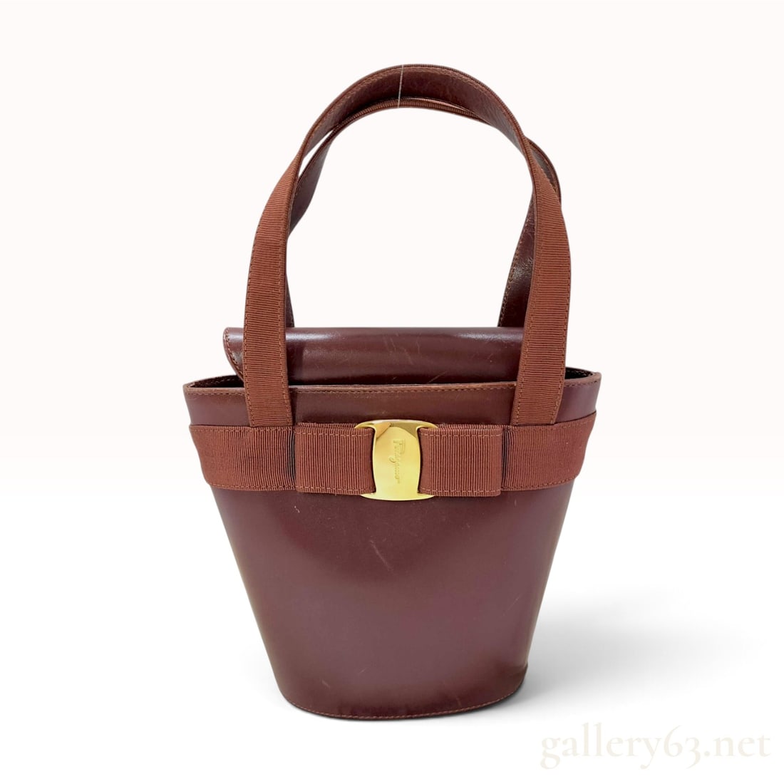 Vintage Salvatore Ferragamo Vara Bow Burgundy Leather Bucket Bag: This Salvatore Ferragamo bucket bag is crafted from smooth burgundy leather featuring the signature Vara bow detail. The exterior design includes a wide grosgrain ribbon trim centered with a gold-tone