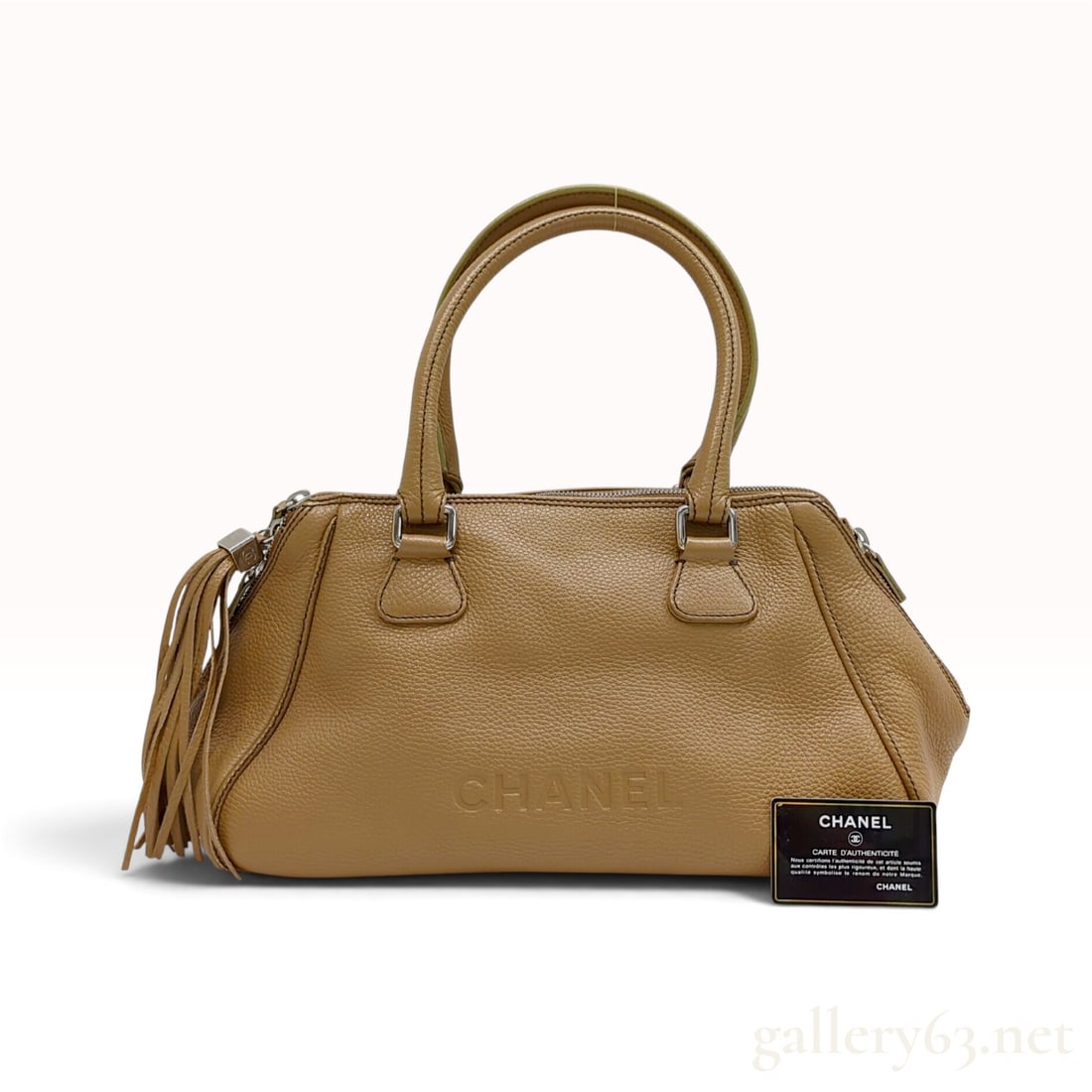 C. 2003 Chanel LAX Tassel Tan Pebbled Leather Bowler Bag with Authenticity Card: This Chanel LAX bowler bag is crafted from tan pebbled calfskin leather featuring a dual-zipper top closure and rolled leather handles. The front of the bag is impressed with capital characters readin