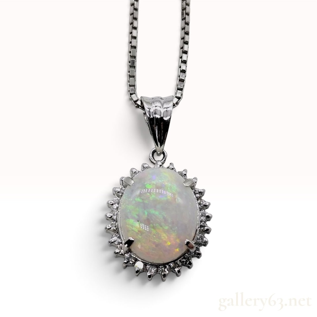 Platinum 1.36ct Opal and 0.25ctw Natural Diamond Halo Pendant Necklace: A platinum, opal, and natural diamond pendant necklace featuring an oval cabochon opal centerpiece. The 1.36ct opal is held in a four-prong setting and exhibits a white body with strong green, orange,