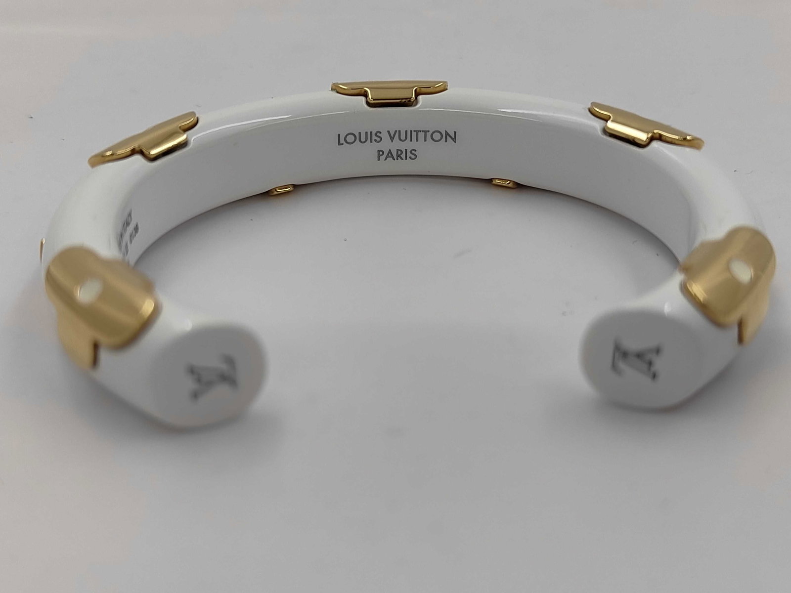 Louis Vuitton Jonc Daily White Resin and Gold-Toned Cuff Bracelet Small: This Louis Vuitton Jonc Daily cuff bracelet is crafted from white resin with gold-toned metal accents. The rigid cuff design features multiple gold-toned metal four-petaled floral motifs from the Loui