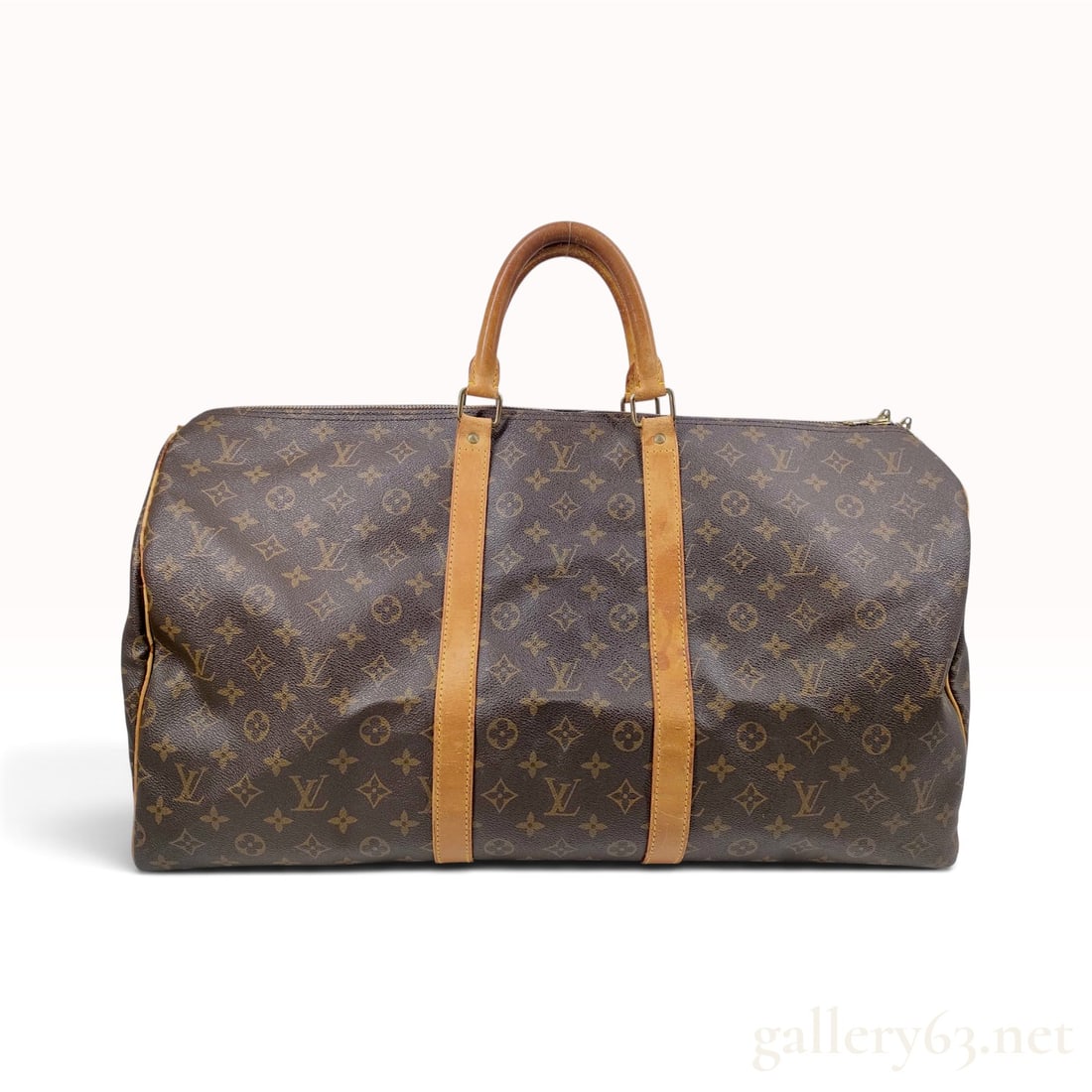 Vintage Louis Vuitton Monogram Keepall 60 Duffle Bag: This Louis Vuitton Keepall 60 duffle bag is constructed from monogram coated canvas with tan Vachetta leather trim and handles. The large travel bag features dual rolled leather handles supported by v