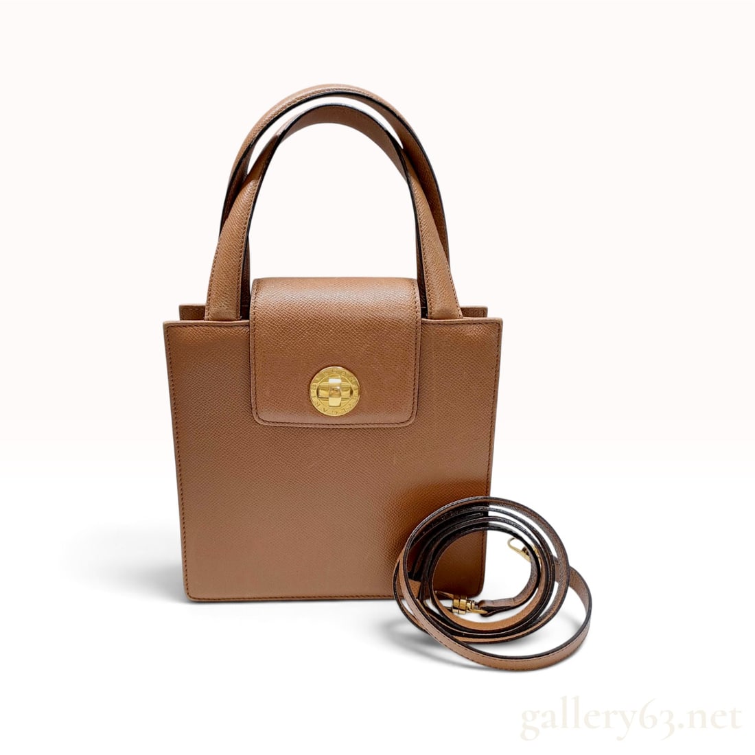 A Vintage Bvlgari Tan Textured Leather Structured Tote Bag with Detachable Shoulder Strap: This Bvlgari structured tote bag is crafted from tan textured cross-grain leather with gold-tone hardware. The square silhouette features dual top handles and a front flap closure secured with a circu