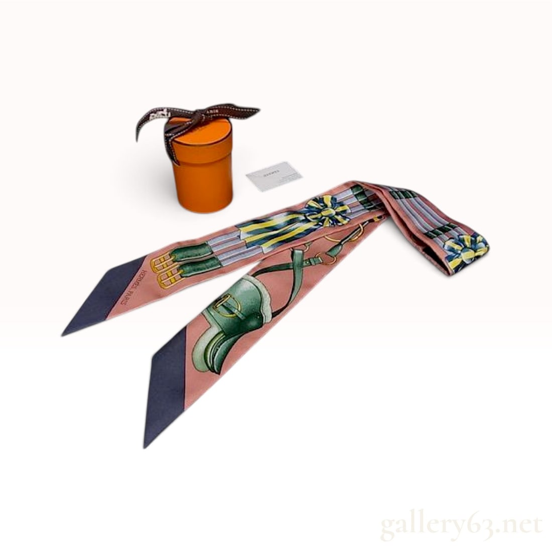 Hermes Jumping Dusty Pink and Navy Silk Twilly Scarf 86 cm with Box: This Hermes Jumping twilly scarf is crafted from 100% silk in a dusty pink and navy colorway. The design features a detailed equestrian motif including a green saddle, stirrup straps with gold-tone bu
