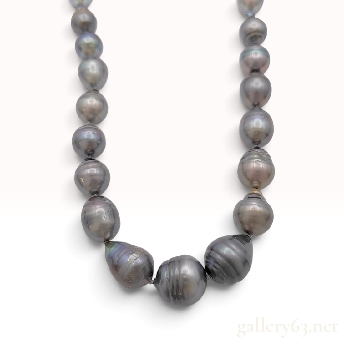 Silver and Graduated Tahitian Circled Baroque Pearl Necklace: This graduated strand of Tahitian cultured pearls is individually knotted on dark silk thread and finished with a silver clasp. The necklace features baroque-shaped pearls with a dark gray body color 