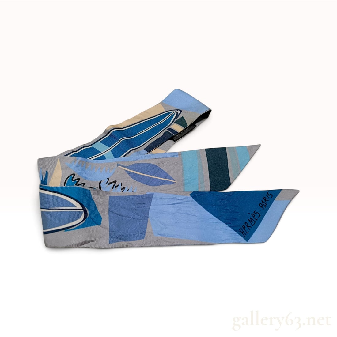 Hermes Sea Surf and Fun Blue and Gray Silk Twilly 86cm: This Hermes silk twilly scarf is designed in the Sea Surf and Fun pattern featuring stylized surfboards and botanical leaf motifs. The composition incorporates a contemporary palette of cerulean, coba