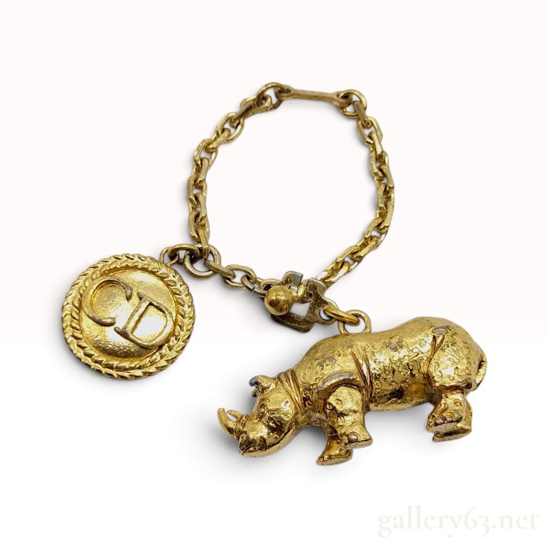 Vintage Christian Dior Gold Plated Rhinoceros Bag Charm: This vintage Christian Dior bag charm is crafted from gold-plated base metal and features a three-dimensional rhinoceros figure alongside a circular monogram medallion. The rhinoceros is modeled with 