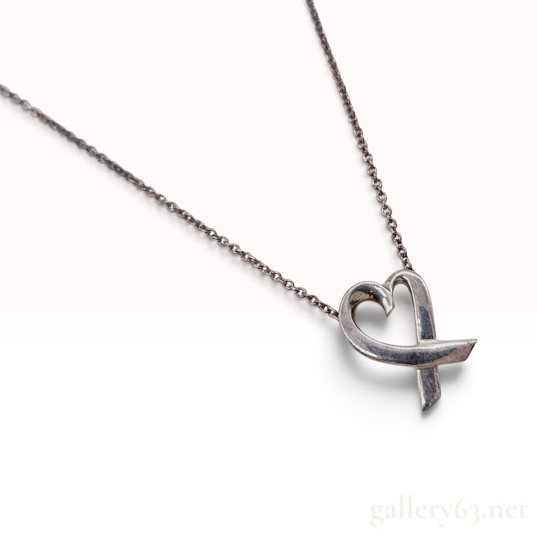 Tiffany & Co. Paloma Picasso Sterling Silver Pendant Necklace: This Tiffany & Co. pendant necklace is crafted from sterling silver and features a stylized heart design by Paloma Picasso. The pendant is composed of a single, continuous looping line that forms a he