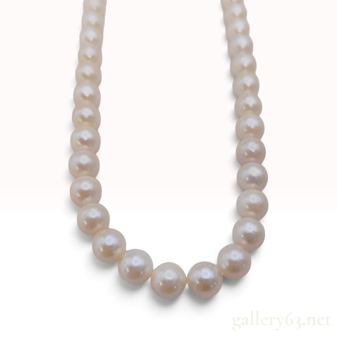 Sterling Silver and Graduated Cultured Pearl Floral Clasp Necklace: This graduated cultured pearl necklace features a single strand of pearls displaying a creamy white body color with rose overtones and high luster. The pearls are graduated in size, measuring approxim