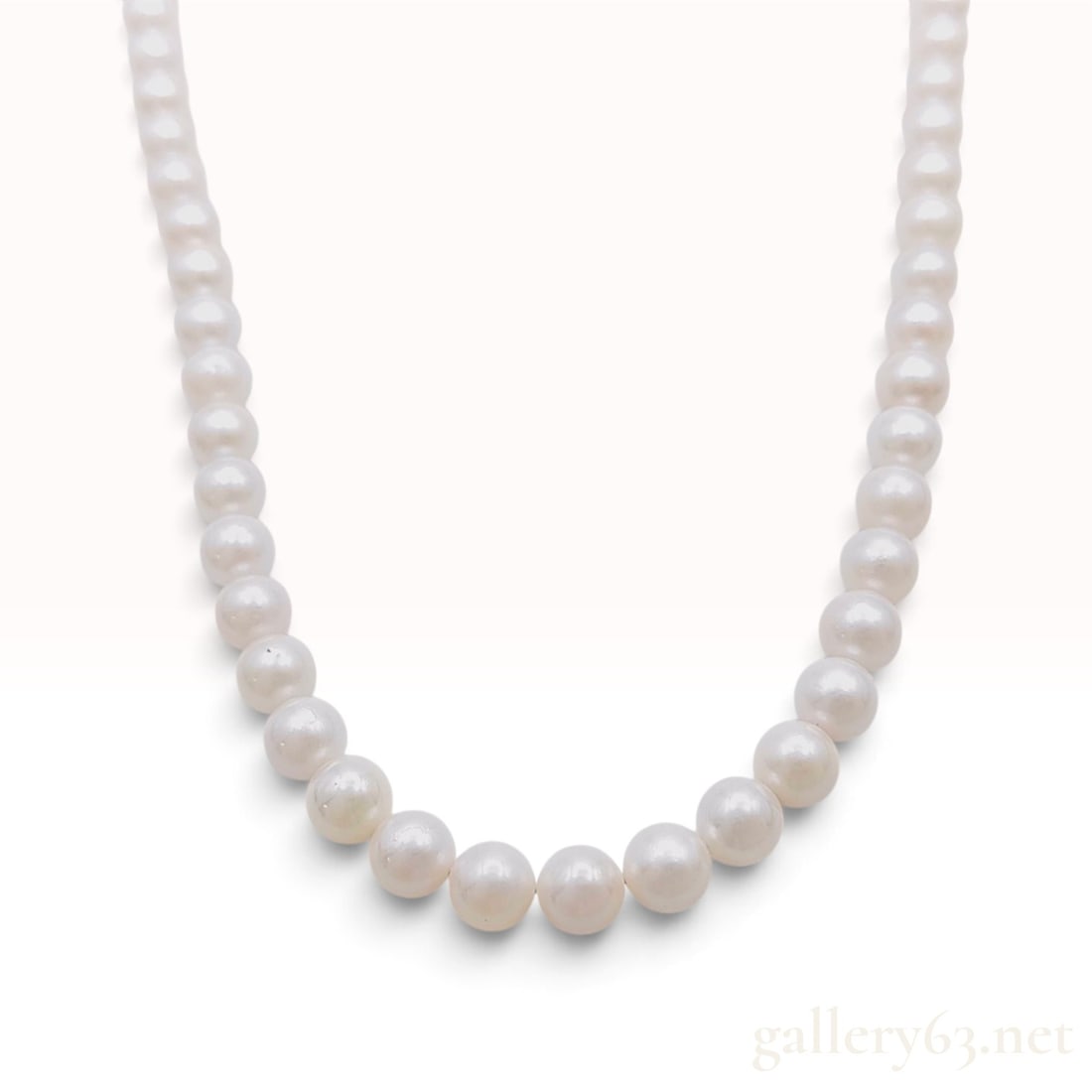 Graduated White Cultured Pearl Necklace with Silver Floral Clasp: This graduated single-strand necklace is composed of white cultured pearls ranging in size from 3.5mm to 7mm. The pearls exhibit cream and rose overtones with consistent luster. Natural surface charac
