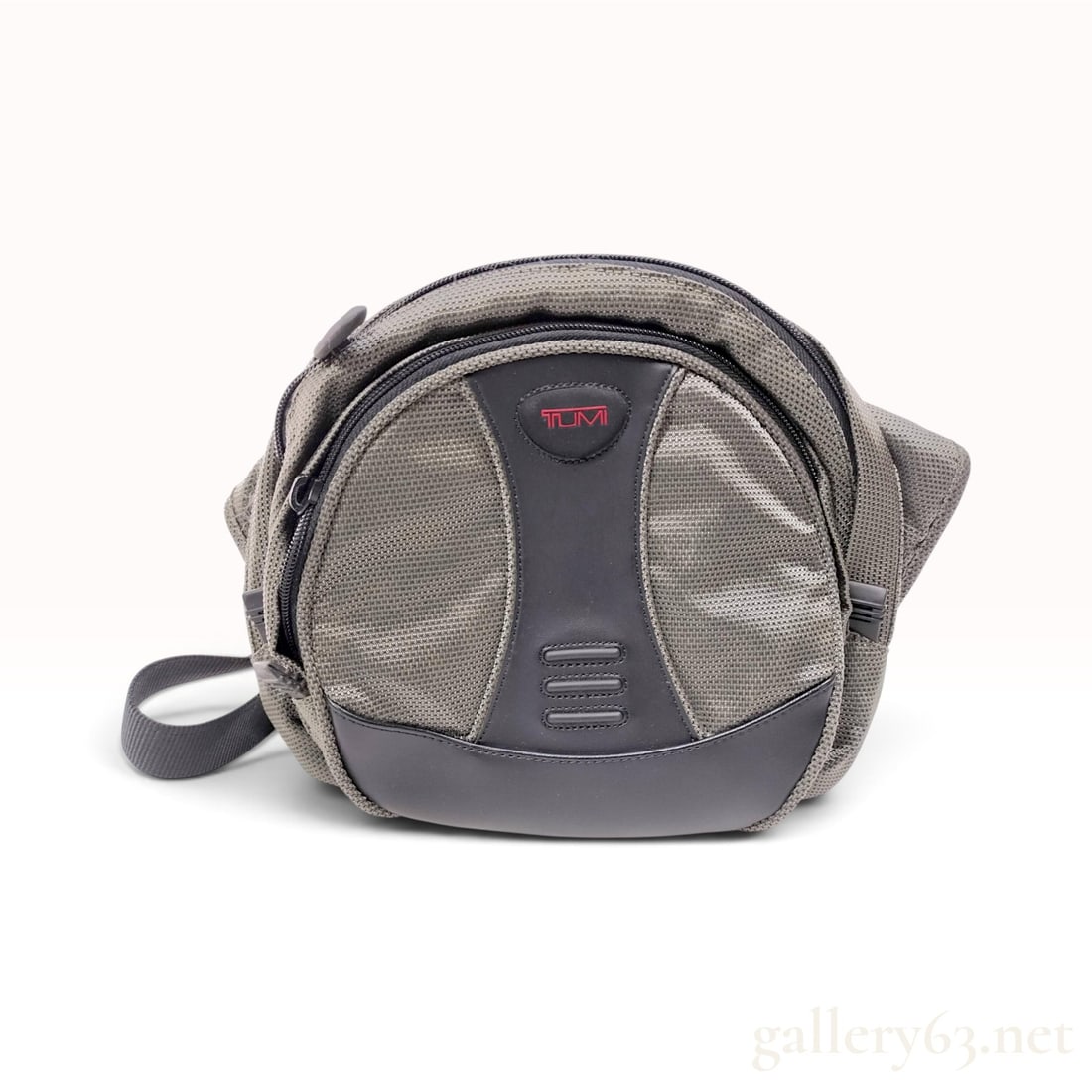 Tumi Grey and Black Ballistic Nylon Camera Side Bag: This Tumi camera side bag is crafted from durable grey and black ballistic nylon with rubberized synthetic trim. The bag features a compact, rounded silhouette with multiple zippered compartments and 