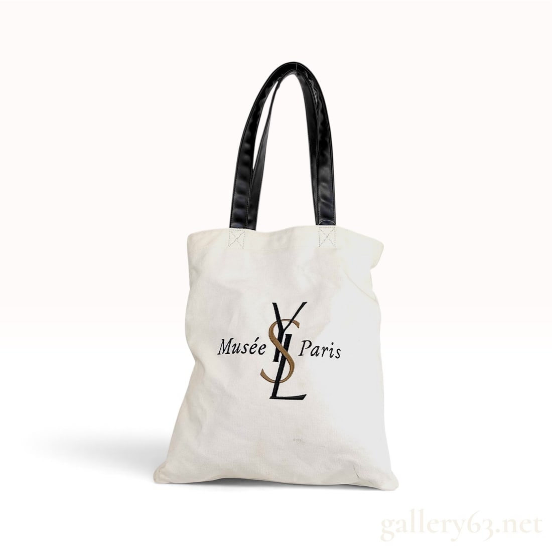 Mus?©e Yves Saint Laurent Paris Exhibition Cream Canvas Tote Bag 38 cm: This Chinese-made Mus?©e Yves Saint Laurent Paris tote bag is constructed from cream-colored canvas featuring flat black synthetic leather handles and a black fabric interior. The front displays a bl