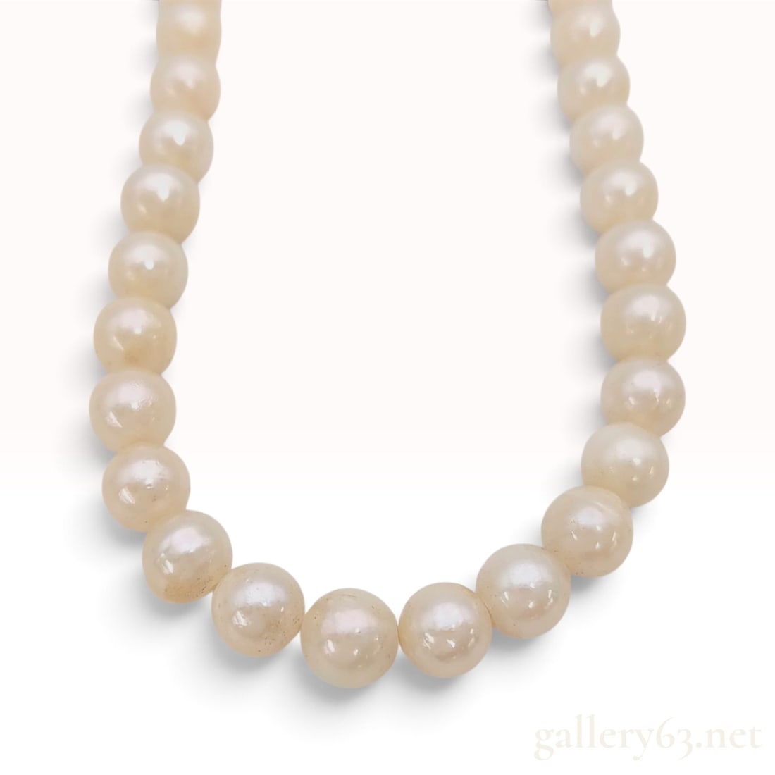 A Vintage Cultured Pearl and Silver Necklace 18 Inch: This single-strand cultured pearl necklace is secured with a round silver filigree box clasp. The clasp features an openwork floral motif centered with a small pearl and is stamped with the word SILVE
