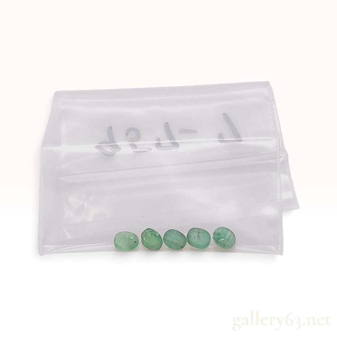 A Set of Five Green Oval Cabochon Gemstones Appearing to be Emerald: This is a set of five loose gemstones cut as oval cabochons with flat bases and polished, domed tops. The stones display a light to medium green color and a translucent to semi-opaque clarity. They co