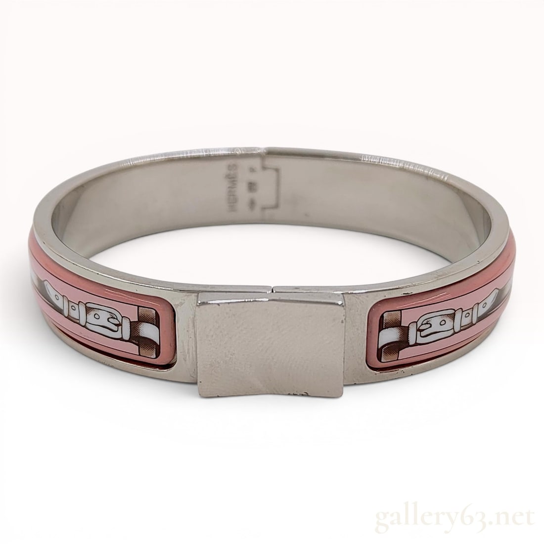 Hermes Loquet Enamel Hinge Bracelet with Pink Belt Motif: This Hermes Loquet hinge bracelet features a delicate pink enamel inlay patterned with a silver-toned belt motif. The piece is constructed with a silver-tone metal frame and utilizes a hinged opening 