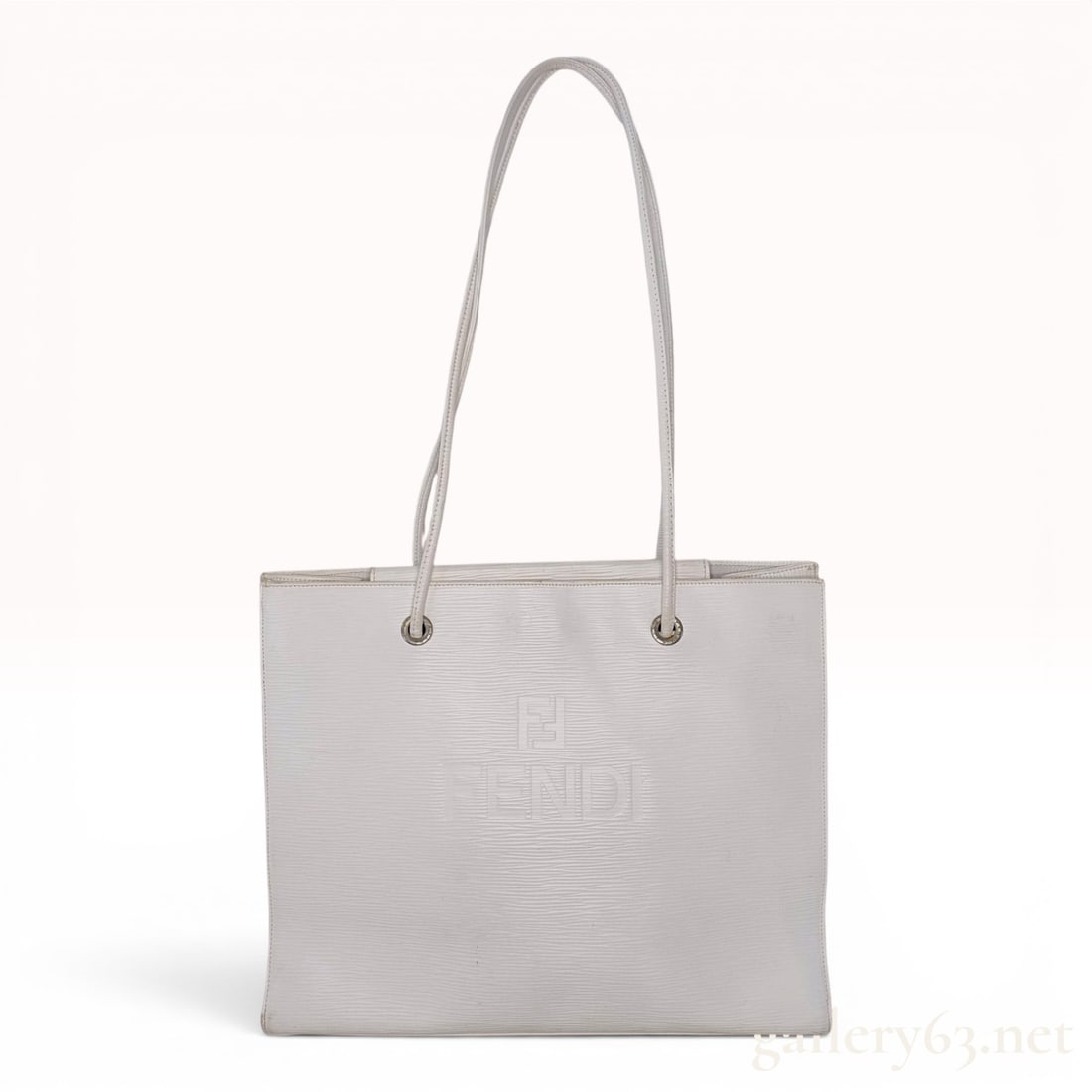 Fendi White Textured Leather Tote Bag: A Fendi tote bag constructed from white leather with a horizontal ribbed texture. The front panel features an embossed FENDI logo and double-F monogram. The bag includes two thin shoulder straps that 