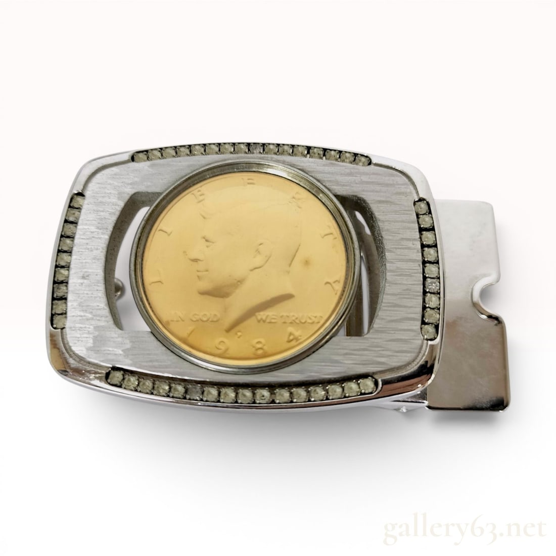 Silver-Toned and Gold-Toned Rhinestone-Bordered 1984 Kennedy Half Dollar Belt Buckle: Attributed to American Coin Treasures, this rectangular men's belt buckle is constructed from a silver-toned base metal with a horizontal brushed finish on the front face. The center of the buckle fea