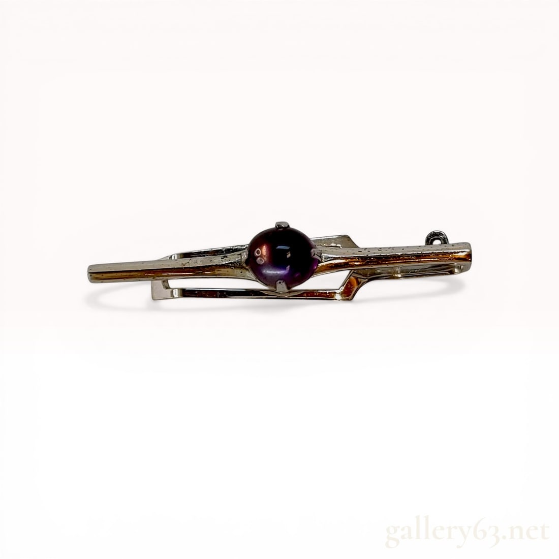 Modernist Silver and Amethyst Cabochon Tie Clip: Mid-to-late 20th-century silver tie clip featuring a modernist geometric design. A central round purple amethyst cabochon is secured in a four-prong setting on a spring-loaded slide mechanism. The rev