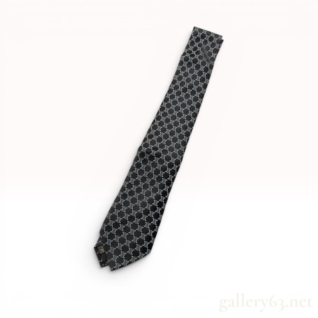 Celine Men's Black Silk Necktie with Silver-Grey Triomphe Motif: Celine 100% silk necktie, modern. This Italian-made tie features an all-over repeating woven silver-grey Triomphe logo motif over a black silk ground. The reverse is finished with a brand-labeled keep
