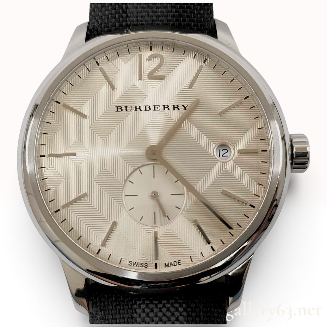 Burberry BU10008 The Classic Round Stainless Steel Quartz Wristwatch: This Burberry The Classic Round wristwatch, model BU10008, features a circular silver-tone stainless steel case. The champagne-colored dial displays a textured geometric pattern and is equipped with a