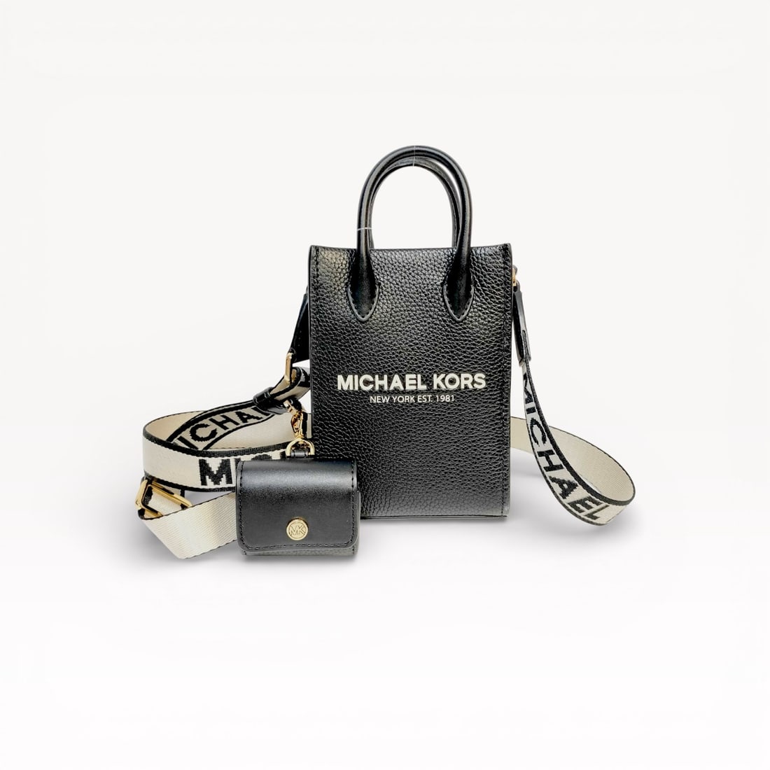 Michael Kors Mirella Small Pebbled Leather Crossbody Bag: Michael Kors Mirella small crossbody bag in black pebbled leather. This structured shopper-style bag features dual rolled handles, gold-tone hardware, and a detachable, adjustable logo-patterned webbi