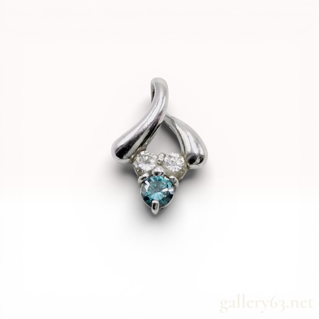Platinum Blue Diamond and Colorless Diamond Bypass Pendant: Platinum pendant in a modern bypass style featuring a three-stone gemstone cluster at the base. The setting comprises a round faceted blue-green treated diamond weighing approximately 0.30 carats, fla