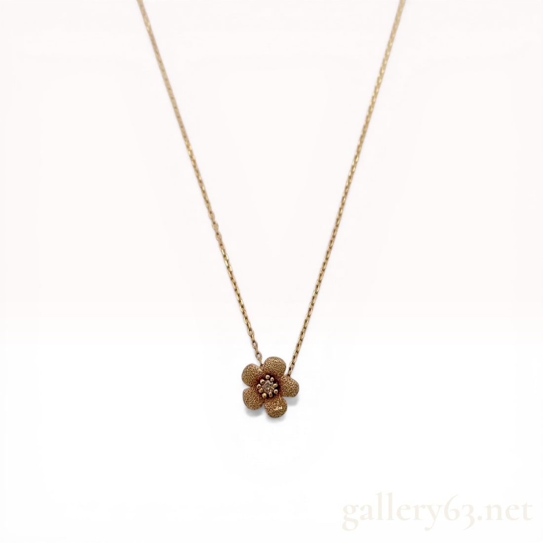 Ete 10 Karat Yellow Gold and Diamond Flower Pendant Necklace: Ete 10 karat yellow gold flower pendant necklace featuring a textured five-petal motif centered with a 0.018 carat round-cut diamond. The pendant is suspended from a fine cable-link chain with a sprin