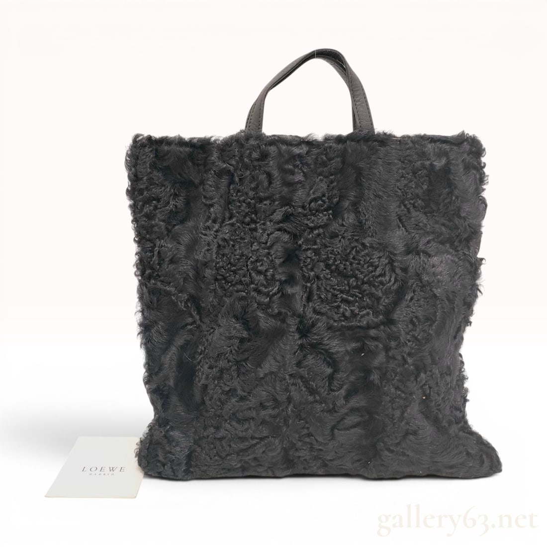 Loewe Madrid Reversible Black Shearling and Leather Tote Bag: This tote bag by Loewe Madrid features a reversible dual-sided design. One side is crafted from textured black curly shearling, while the opposing side is made of smooth black leather. The bag is equi