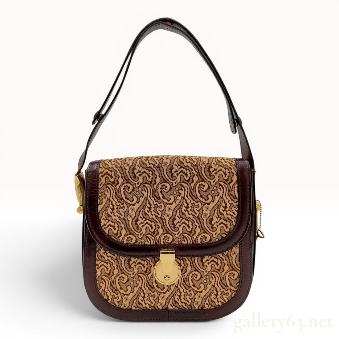 A Vintage Les Must de Cartier Bordeaux Leather and Tapestry Shoulder Bag: A vintage Les Must de Cartier shoulder bag featuring a signature bordeaux leather trim and a tapestry-woven fabric body with a beige and brown scrolling paisley pattern. The bag has a rounded, saddle-