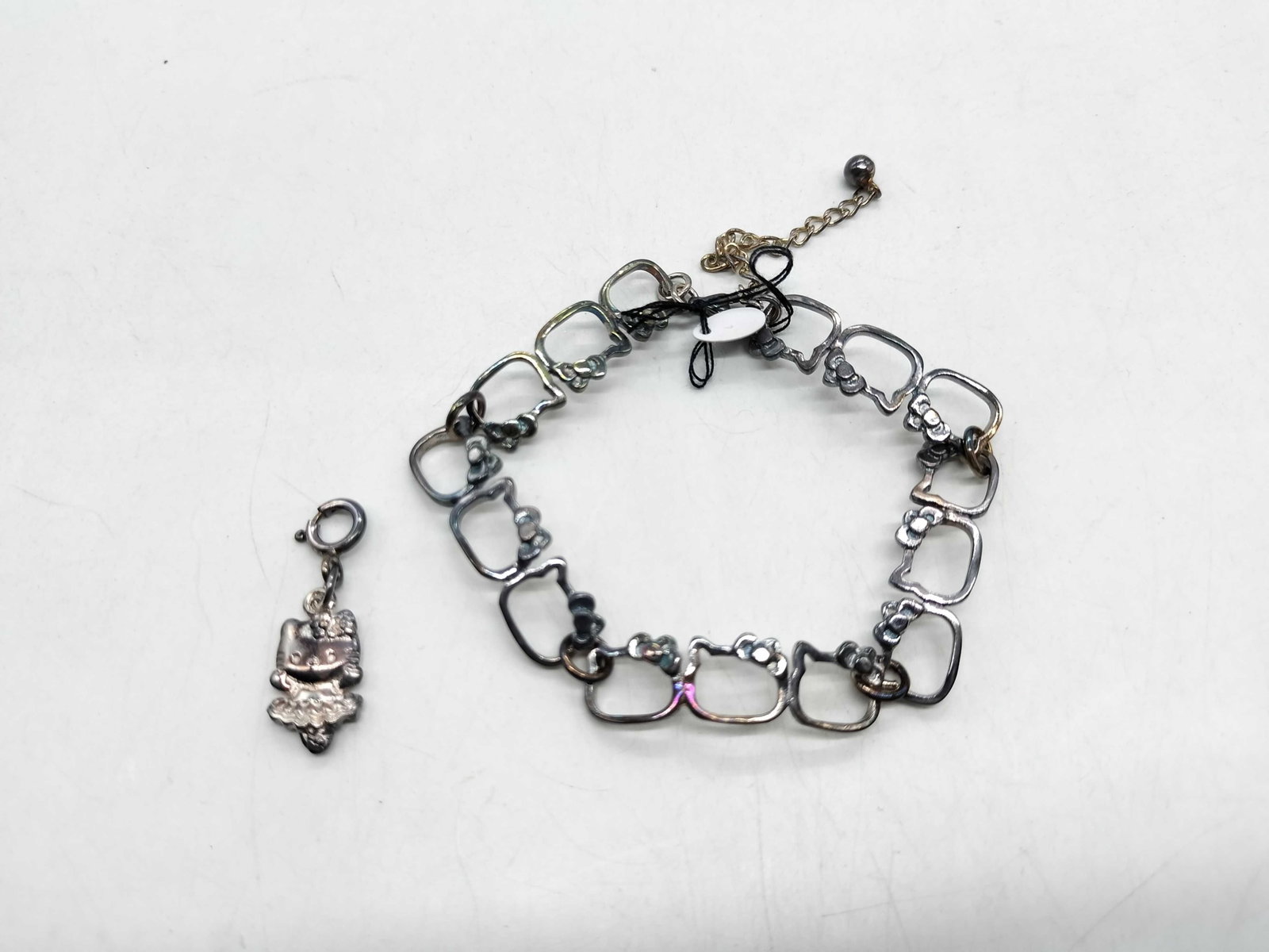 Sanrio Sterling Silver Hello Kitty Link Bracelet and Figural Charm Set: This two piece jewelry set is an officially licensed Sanrio product featuring Hello Kitty designs. The set consists of a link bracelet and a separate figural charm. The bracelet is constructed of inte