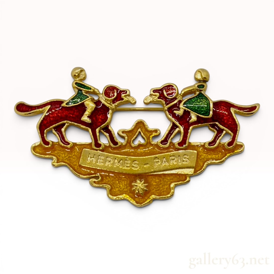 Hermes Vintage Multicolor Enamel and Gold-Tone Dog Motif Brooch: This vintage Hermes brooch features a whimsical figural design depicting two stylized red hounds facing one another, each mounted by a rider in a green coat. The figures are positioned above a scrolle