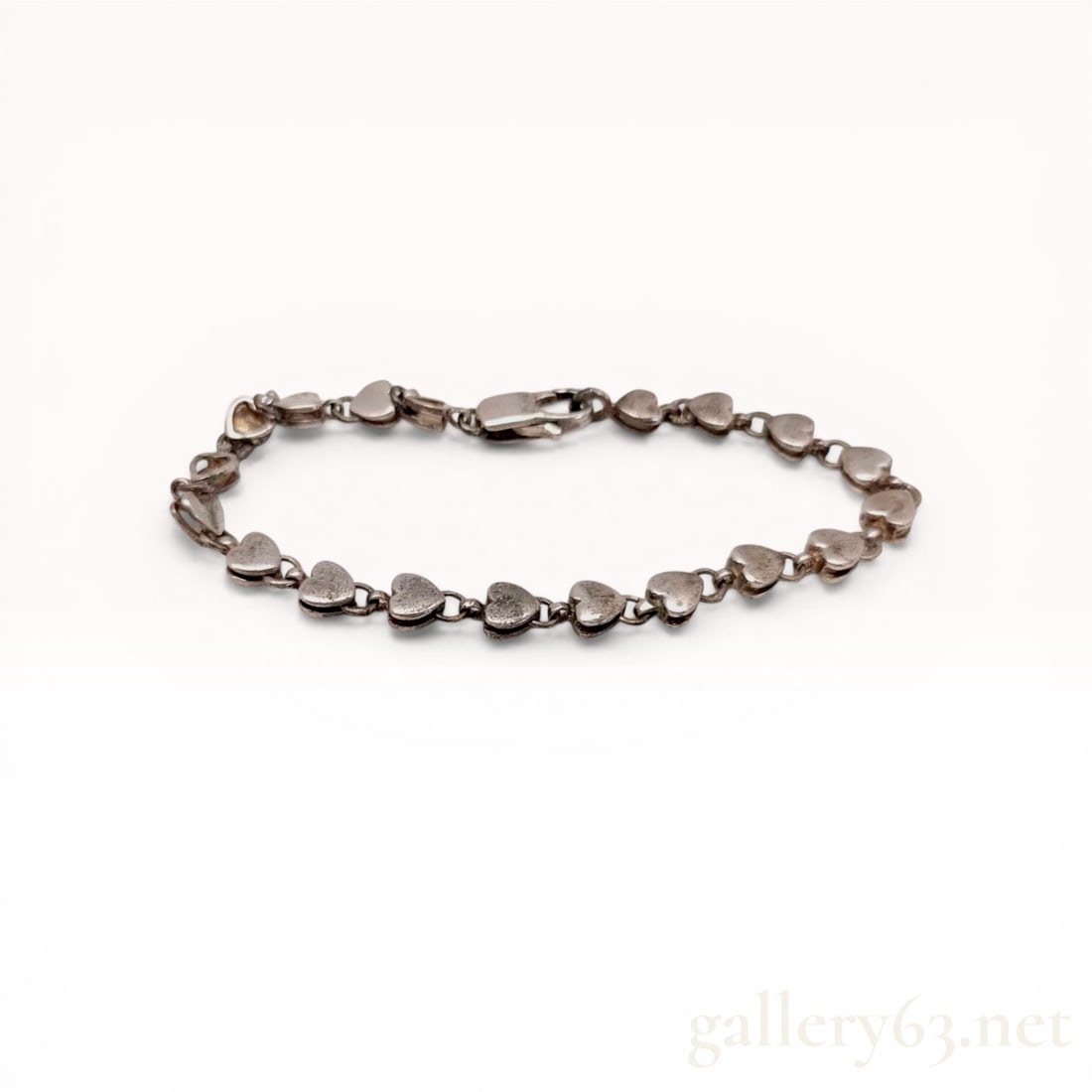 Tiffany & Co. Sterling Silver Puffed Heart Link Bracelet: Tiffany Co. Sterling silver link bracelet featuring a continuous row of puffed heart-shaped links. Each solid link is interconnected by small circular jump rings and terminates in a lobster claw