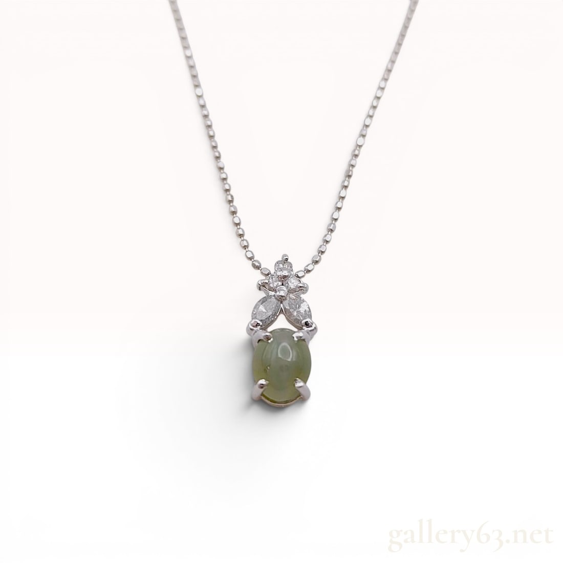18K White Gold Cat's-Eye Gemstone and Diamond Pendant Necklace: An 18 karat white gold pendant necklace featuring a central chatoyant gemstone. The open-back decorative pendant is set with a 1.0 carat oval cabochon pale green-gray cat's-eye gemstone accented by tw