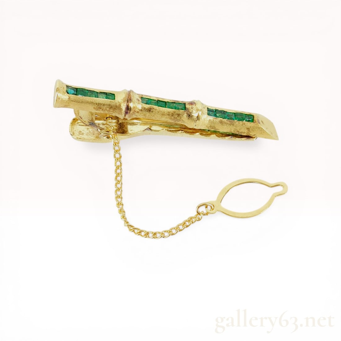 Gold-Plated Silver Bamboo Motif Tie Clip with Emeralds: A vintage tie clip featuring a textured bamboo motif bar channel-set with fifteen square-cut green emeralds. The piece is constructed of silver with a gold-plated finish and includes a spring-loaded a