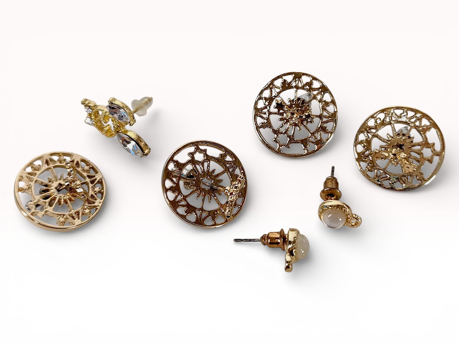 An Assortment of Gold-Tone Fashion Stud Earrings Including Market Gate Style Filigree: An assortment of gold-tone fashion stud earrings featuring circular filigree and cabochon designs. The collection includes two pairs of openwork filigree studs in the style of Charleston market gate p