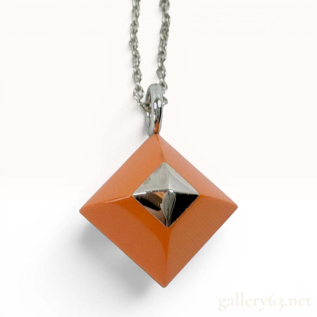 Hermes Medor Cupidon Orange Enamel and Silver Tone Pendant Necklace: A designer pendant necklace by Hermes, specifically the Medor Cupidon model. The pendant features a square pyramid form inspired by the iconic Medor stud, finished in signature Hermes orange enamel. I