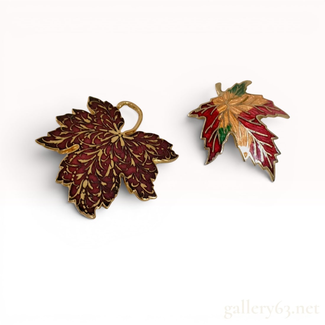 Two Metropolitan Museum of Art MMA Gold-Tone and Enamel Maple Leaf Brooches: Two Metropolitan Museum of Art (MMA) gold-tone and enamel maple leaf brooches, including one dated 1985. The larger piece features stylized gold foliate scrollwork on a dark red enamel ground, while t