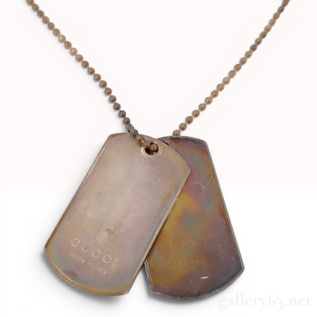 Gucci Sterling Silver Double Dog Tag Necklace: A designer necklace by Gucci featuring two rectangular dog tag pendants suspended from a ball chain. The piece is constructed from sterling silver and features a barrel screw clasp. Each pendant is st