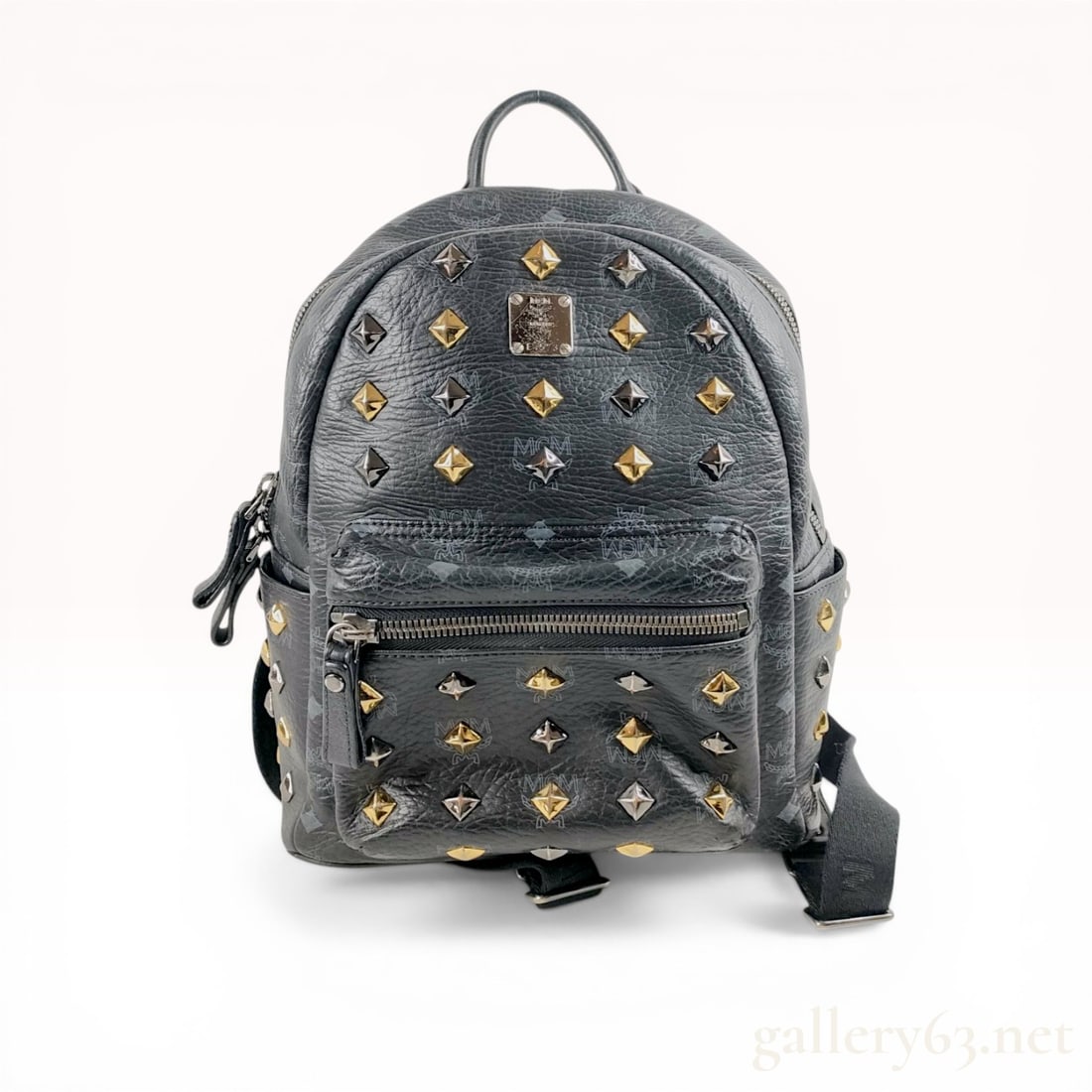 MCM Black Visetos Stark Side Stud Bebe Boo Backpack: MCM Stark Bebe Boo backpack in black Visetos monogram coated canvas with black leather trim. Features mixed-metal pyramid side studs, a front zippered pocket, two side slip pockets, and adjustable lea