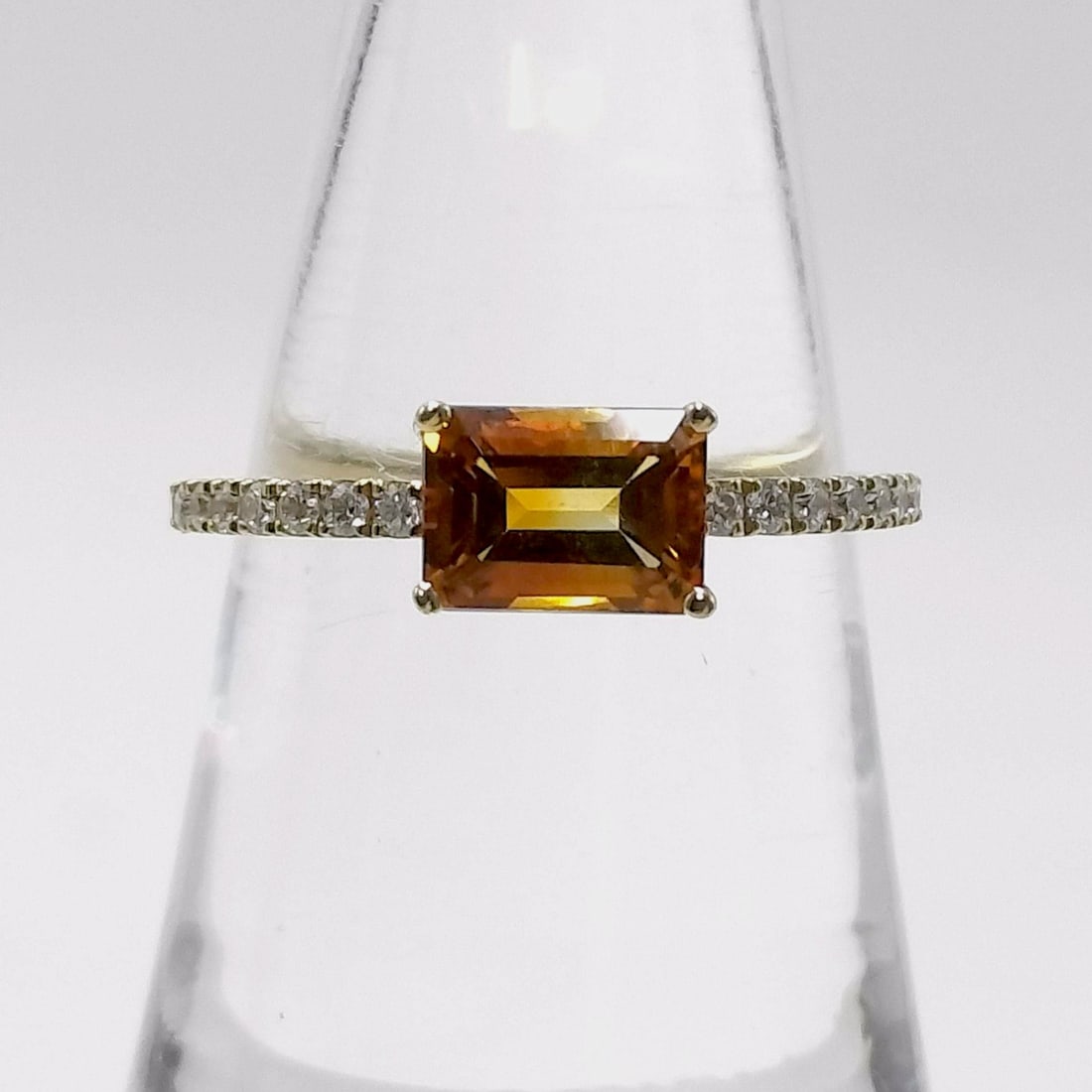 18K Yellow Gold Emerald Cut Citrine and Diamond Ring: Modern fashion ring featuring a central emerald-cut citrine weighing approximately 1.05 carats. The 18 karat yellow gold band is accented by sixteen round brilliant-cut diamonds totaling approximately