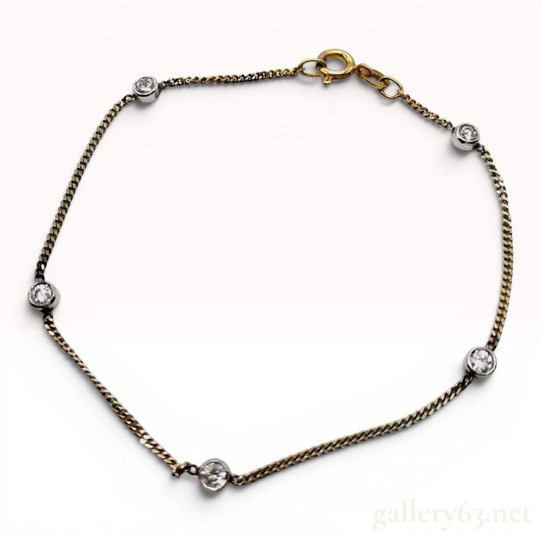 Unoaerre Italian 14K Yellow and White Gold Station Bracelet: An Italian 14 karat yellow gold curb link bracelet featuring five white metal bezel-set stations. Each station contains a round brilliant-cut clear stone, measuring approximately 3mm in diameter. The 