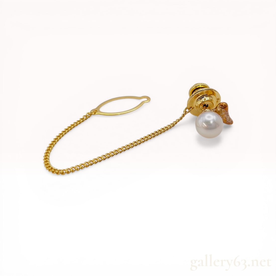 Mikimoto 18K Yellow Gold and Cultured Pearl Tie Tack: Mikimoto tie tack featuring a single round white cultured pearl set against a stylized 18K yellow gold foliate motif. The pin head is stamped on the reverse with the Mikimoto shell logo and 18K, attac